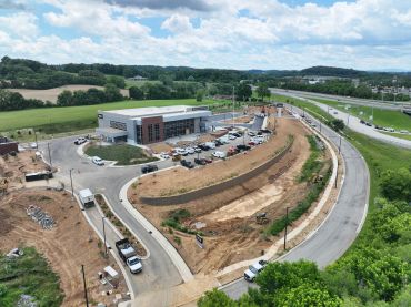 A construction site with a building and surrounding roads under a partly cloudy sky.