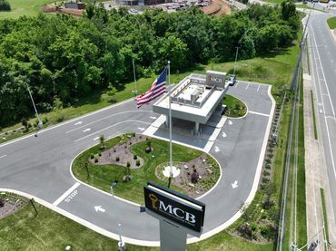 Aerial view of MCB bank entrance with flagpole and surrounding greenery.