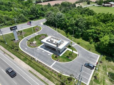 A modern security checkpoint with a single lane and landscaping.