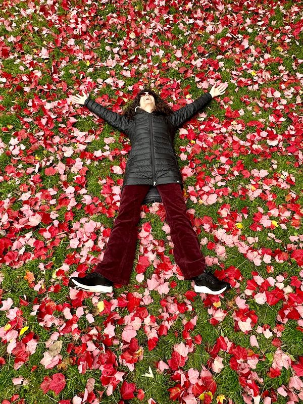 Picture of Jenny smiling lying on the ground with pink and red leaves