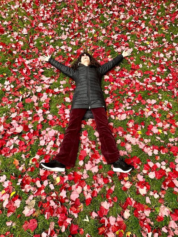 Picture of Jenny smiling lying on the ground with pink and red leaves