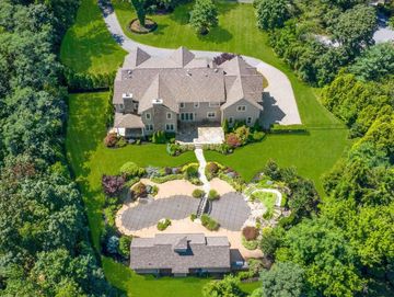A large house with a circular driveway surrounded by lush greenery.