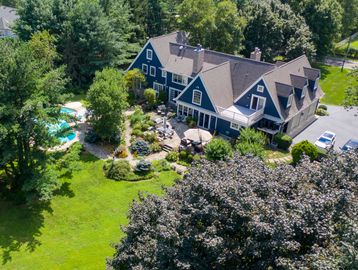 A large blue house surrounded by lush greenery and a swimming pool.