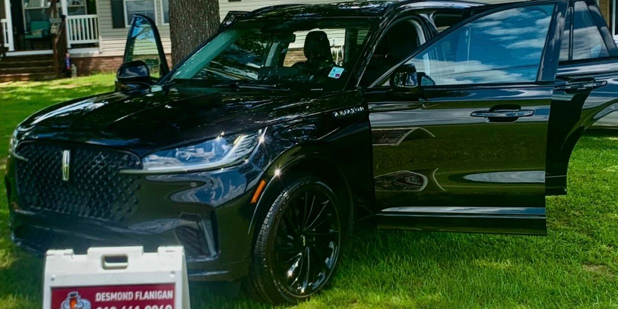 Shiny black Lincoln SUV with doors open on a grassy lawn.