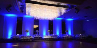 Elegant event space with blue lighting and chandeliers.