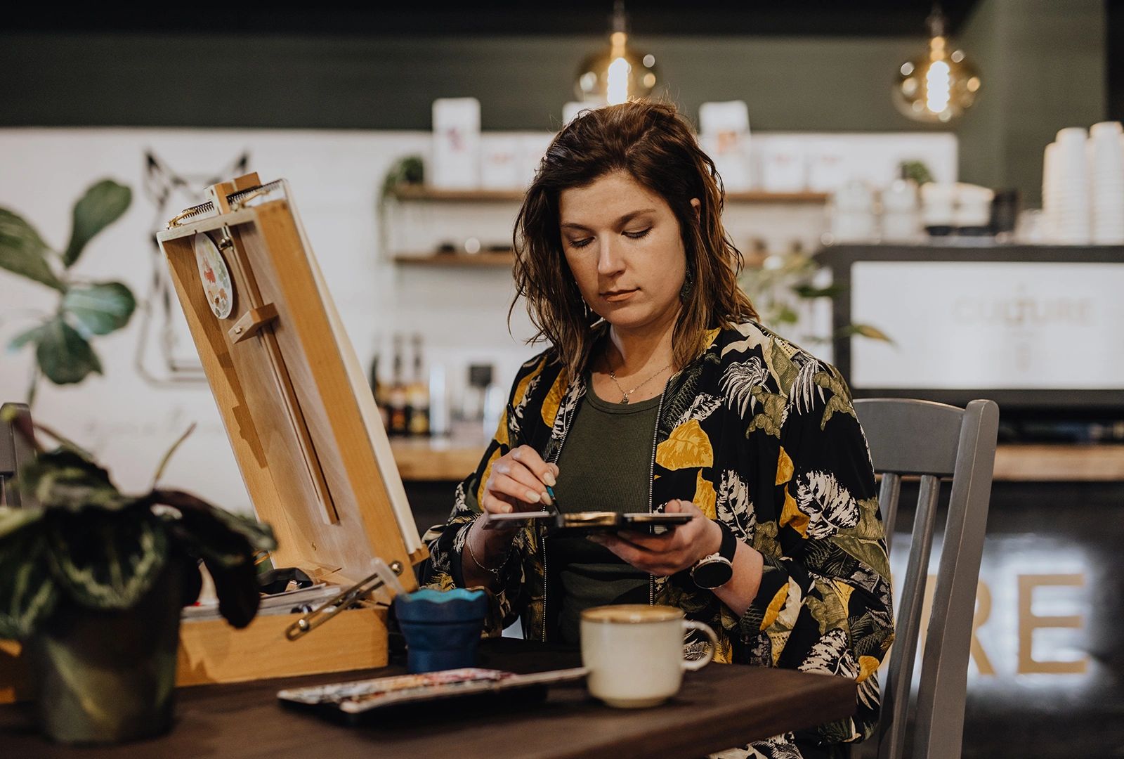 Marijke painting with her table top easel at a coffee shop. 