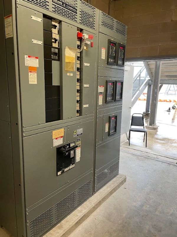 Large industrial electrical control panel inside a facility near an open door.