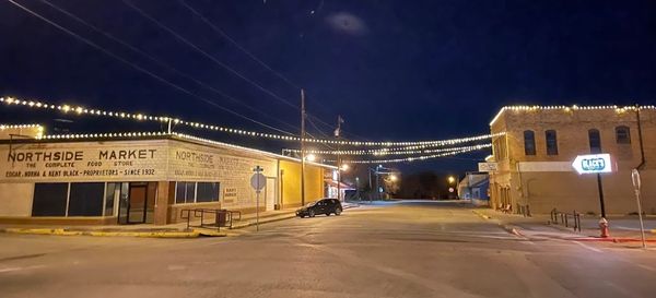 Quiet street at night with string lights and Northside Market storefront.