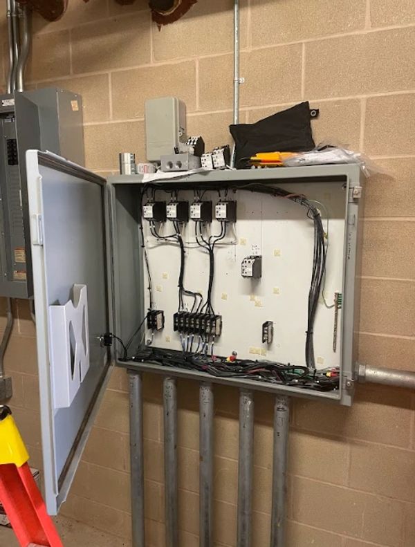 Open electrical panel with wiring and circuit breakers inside.