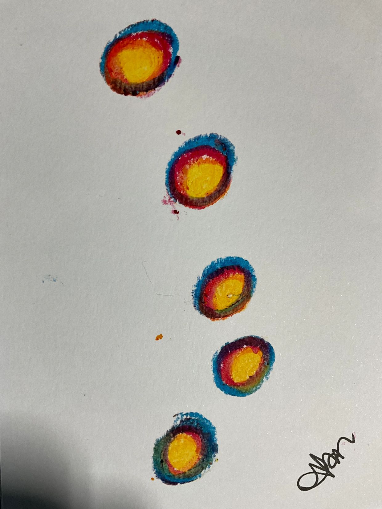 Five colorful concentric circles painted on white paper.