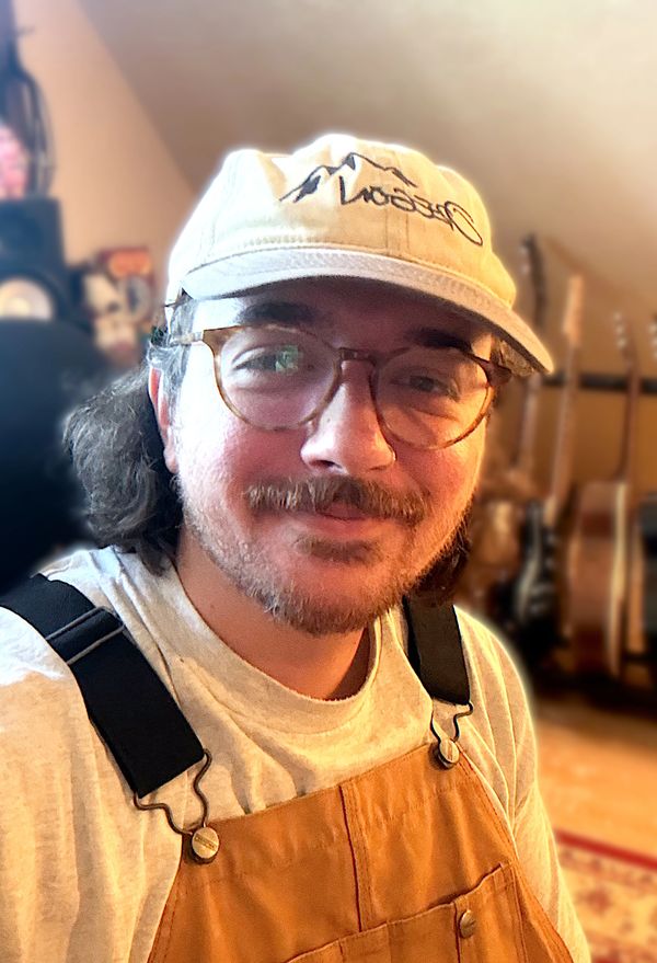 Close-up of a smiling man with glasses and a cap.