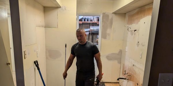An image of one of the owners of Black and White Renovations working on demoing a kitchen.