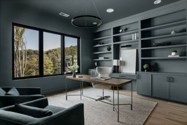 Modern home office with gray walls and large window.