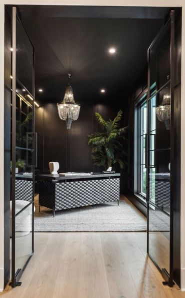 Modern black home office with chandelier and glass doors.