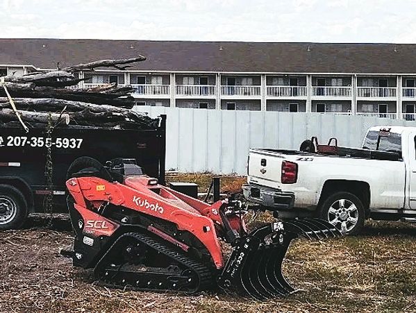White pickup truck and Kubota loader with junk removal trailer full of branches.
