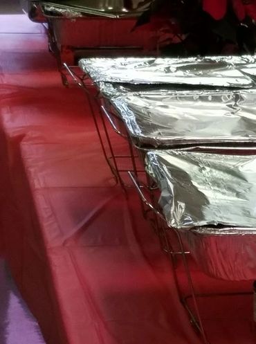 Aluminum trays covered with foil on a red tablecloth.