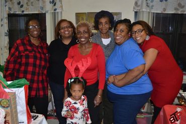 A joyful group of women with a child wearing reindeer antlers at a holiday gathering.