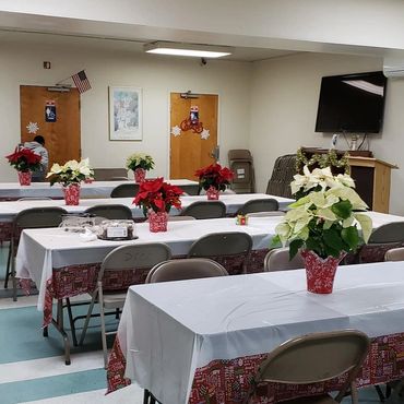 Indoor room with tables decorated with poinsettias and festive tablecloths.