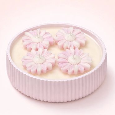 Round tray with four pink flower-shaped candles on a creamy base.