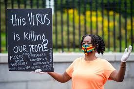An African American woman with a sign highlighting the impact on African Americans