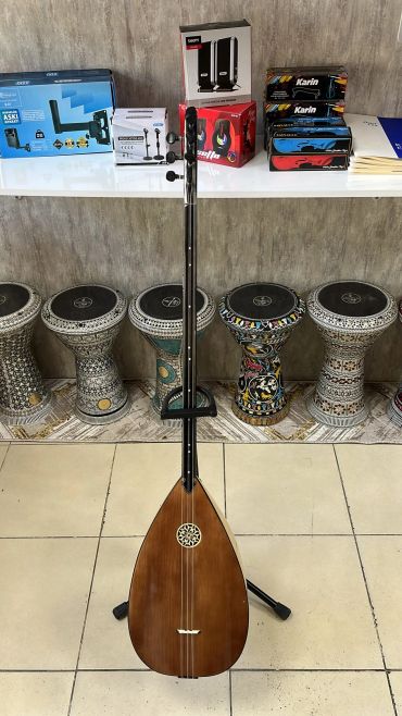 Uzun saplı müzik aleti, arka planda darbuka çeşitleri.