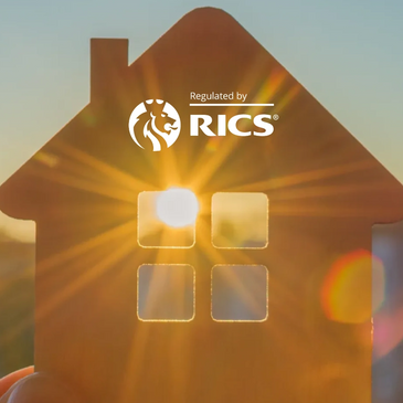 Hand holding a wooden house cutout with sunlight shining through its window.