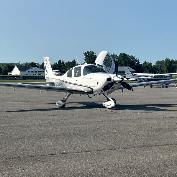 Small white airplane on runway with open door.