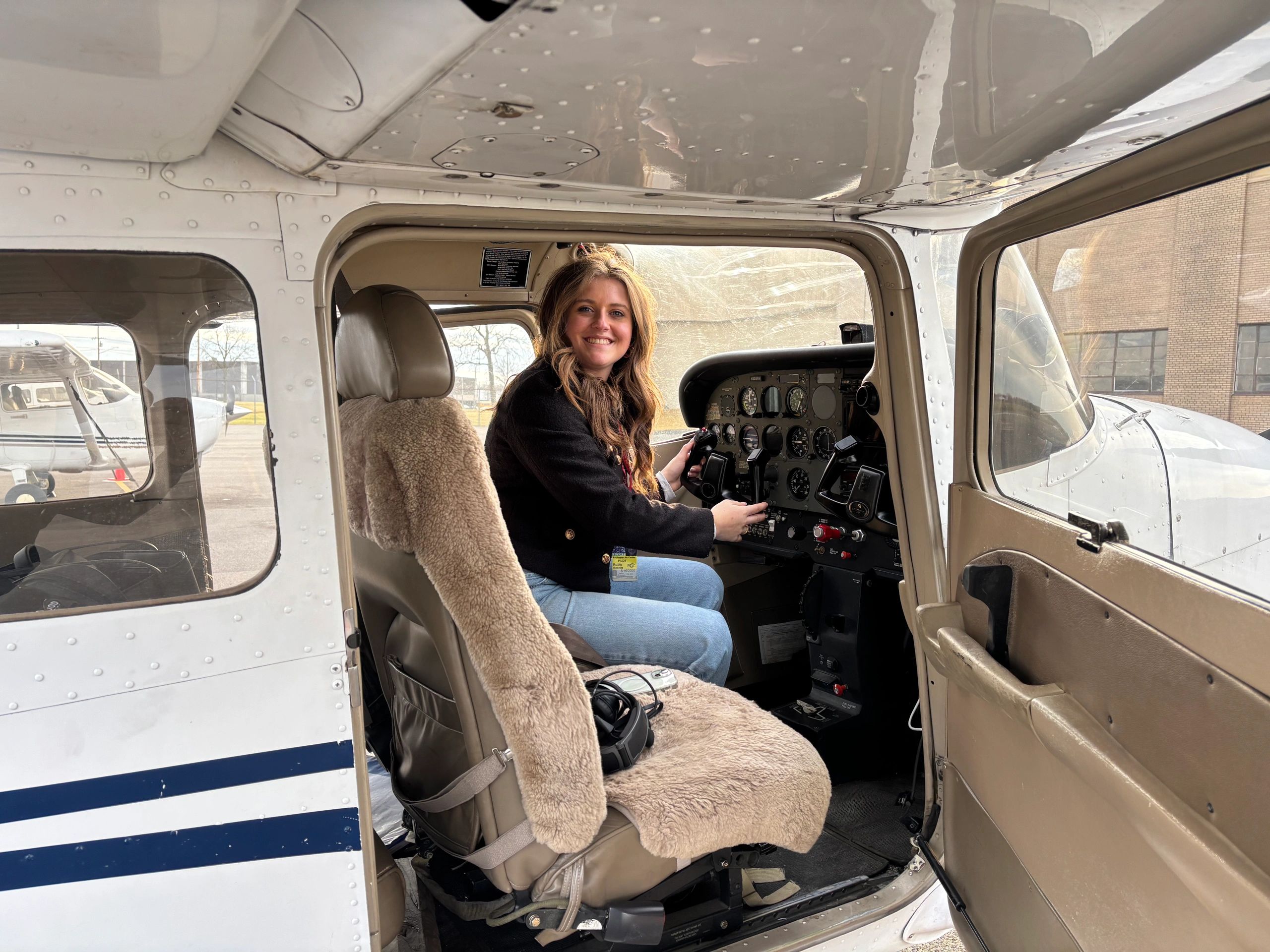 Woman smiling inside a small airplane cockpit.