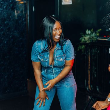 Woman laughing joyfully in a denim outfit.