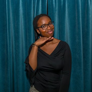 Woman posing with hand under chin, smiling.