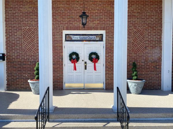 Entrance of First Baptist Church decorated with wreaths and red bows.
