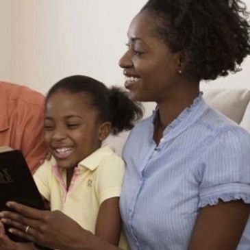 A woman and young girl read the Bible together.