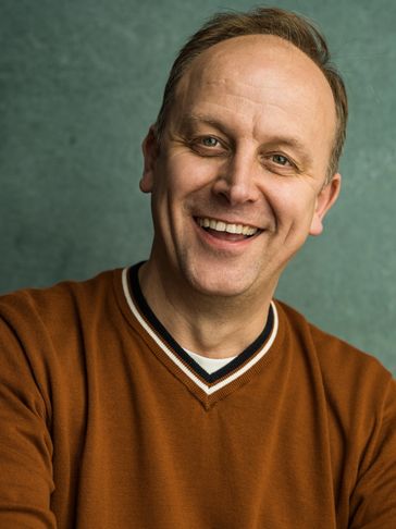 Smiling man in a brown sweater.