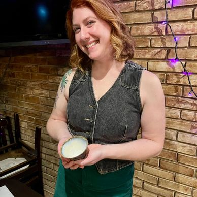 Smiling woman holding a cup with a creamy drink in a cozy setting.