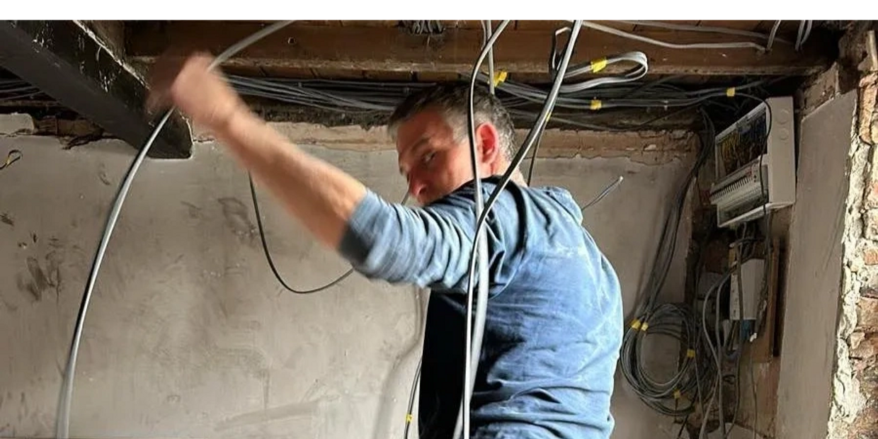 An electrician running cables in a ceiling.
