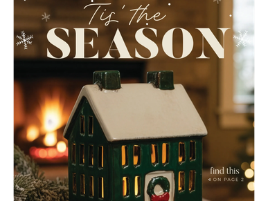 Festive ceramic house with a snowy roof in front of a warm fireplace.
