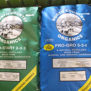 Bags of North Country Organics natural fertilizer in green and blue packaging.