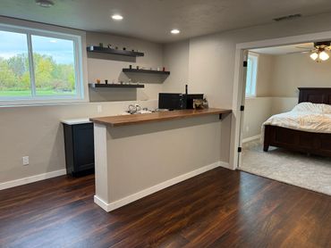 Modern home office space adjacent to a cozy bedroom with wooden flooring.