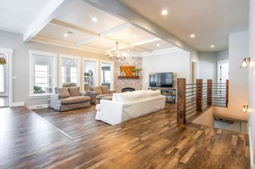 Bright modern living room with wooden floors and neutral furniture.