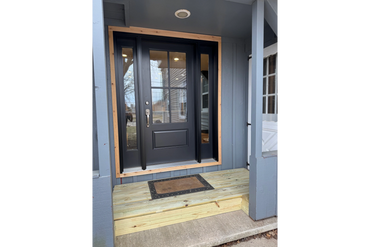 Modern black front door with wooden frame and new wooden porch steps.