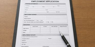An employment application form with a pen on top, ready to be filled out.