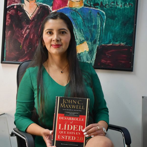 Mujer sostiene un libro de liderazgo en una oficina.
