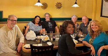 A group of six friends enjoying a meal together at a cozy restaurant.