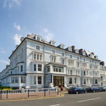 Elegant white multi-story building under a clear blue sky.