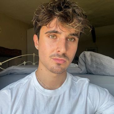 Young man with light brown hair and earrings taking a selfie.