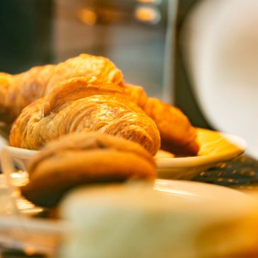 Golden croissants and cookies on plates in warm lighting.