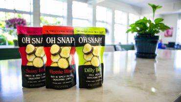 Three colorful bags of OH SNAP! vegetable snacks on a kitchen counter.