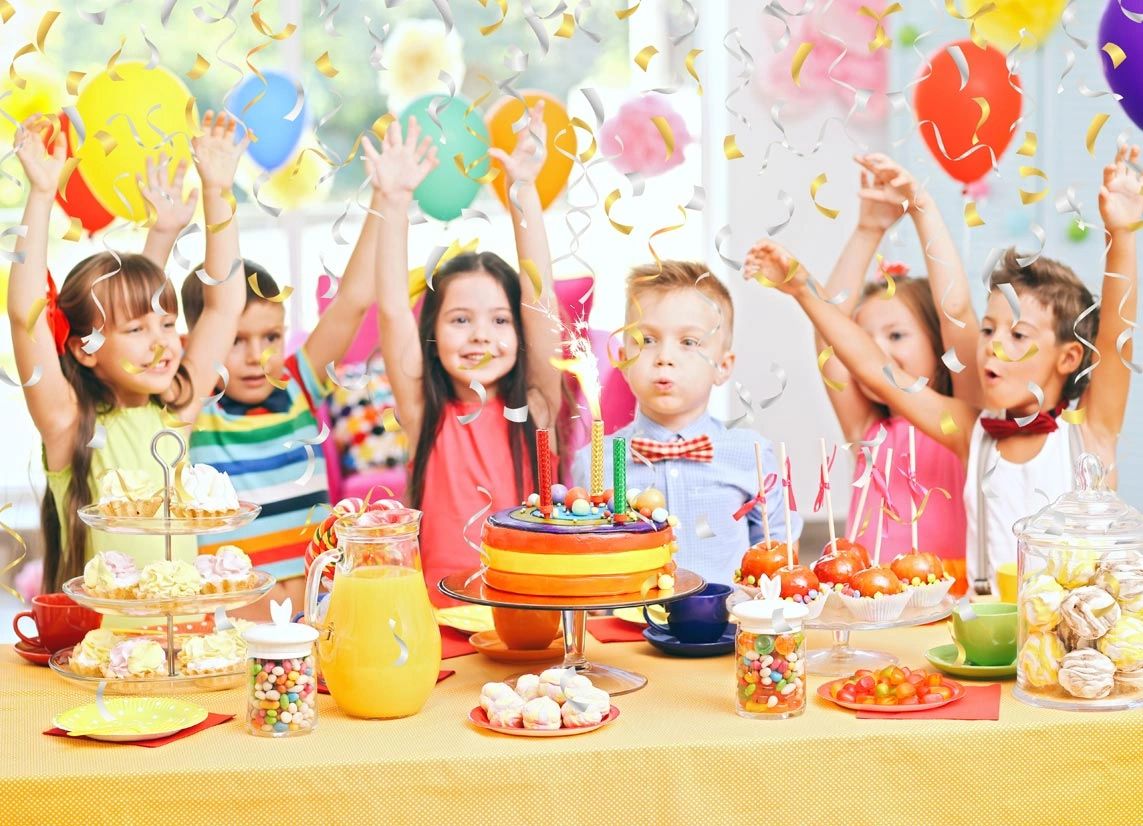 Children celebrating a colorful birthday party with cake and balloons.