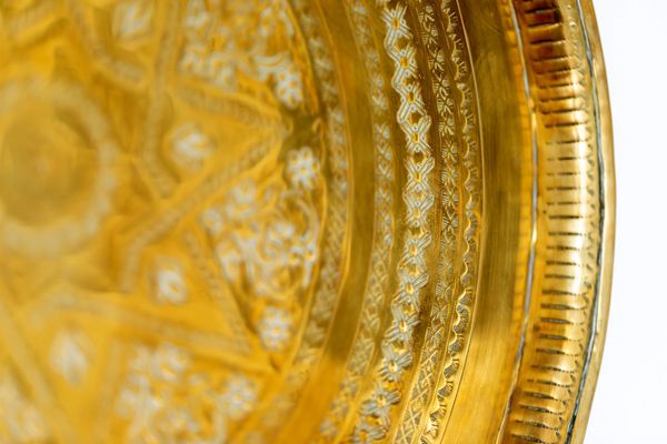 Close-up of an ornate gold decorative plate with intricate patterns.