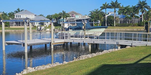 Boat dock with a boat lift on a calm waterfront in a residential area.